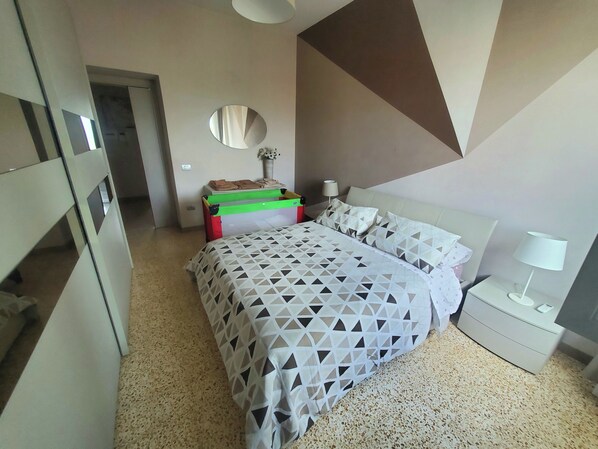 A modern bedroom with a bed, a bedside table, a lamp, and a dresser.