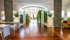 A spacious lobby with a wooden floor, stone pillars, and a glass ceiling. - 5313 Coral Suite The Beach Club (Palm Cove)
