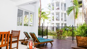 A balcony with wooden chairs, a table, and a potted plant. - 5313 Coral Suite The Beach Club (Palm Cove)