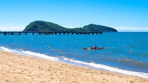 A beach with a pier extending into the sea, a person in a kayak, and a sandy shore. - 5313 Coral Suite The Beach Club (Palm Cove)