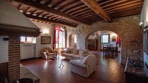 Amplia sala de estar con un alto techo de madera, un arco de piedra y una chimenea.