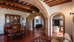 Amplia sala de estar con una mesa y sillas de madera, un tapete estampado y una chimenea.