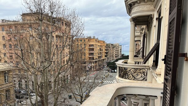 A balcony with a view of a city street, buildings, and a clear sky.