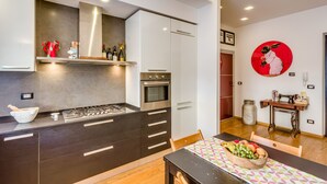 A modern kitchen with dark cabinetry, stainless steel appliances, and a dining area with a wooden table and chairs.