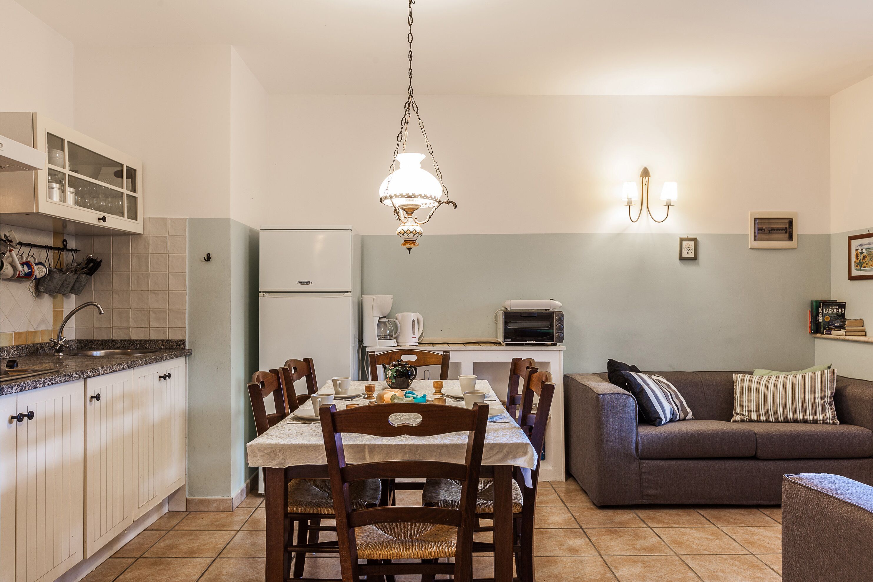 Une cuisine de taille réduite comprenant une table à manger, des chaises, un canapé et une machine à café.