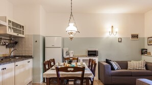 Ett kompakt kök med ett matbord, stolar, en soffa och en hängande lampa.