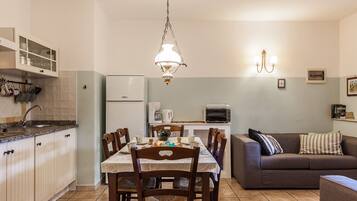 Une cuisine de taille réduite comprenant une table à manger, des chaises, un canapé et une machine à café.