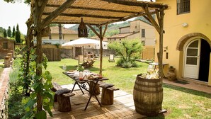 An outdoor patio with a wooden table set for dining, surrounded by rustic wooden stools and a barrel. - Tuscan rustic house with exclusive private garden (Montemagno)