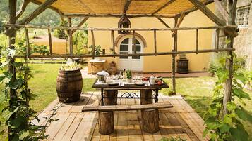 Un espace de restauration en plein air avec une table et des bancs en bois rustique, le tout entouré d’une structure en forme de pergola.
