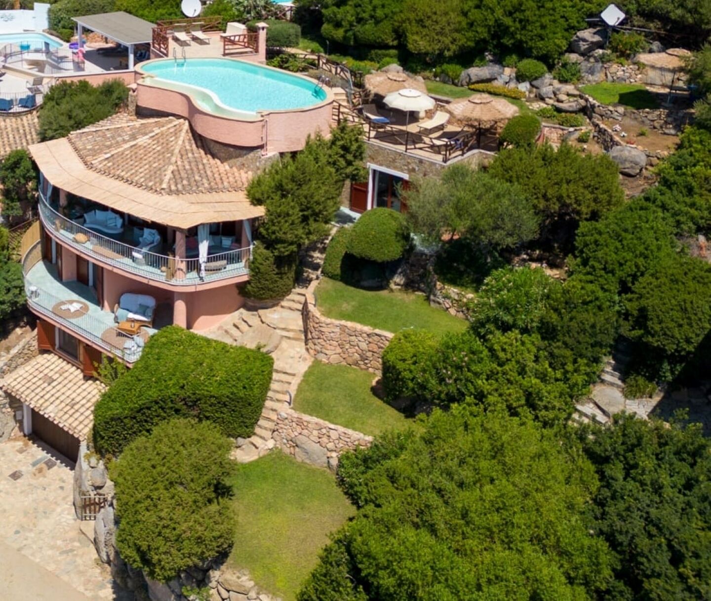 A two-story house with a swimming pool, a covered patio, and a well-maintained garden.