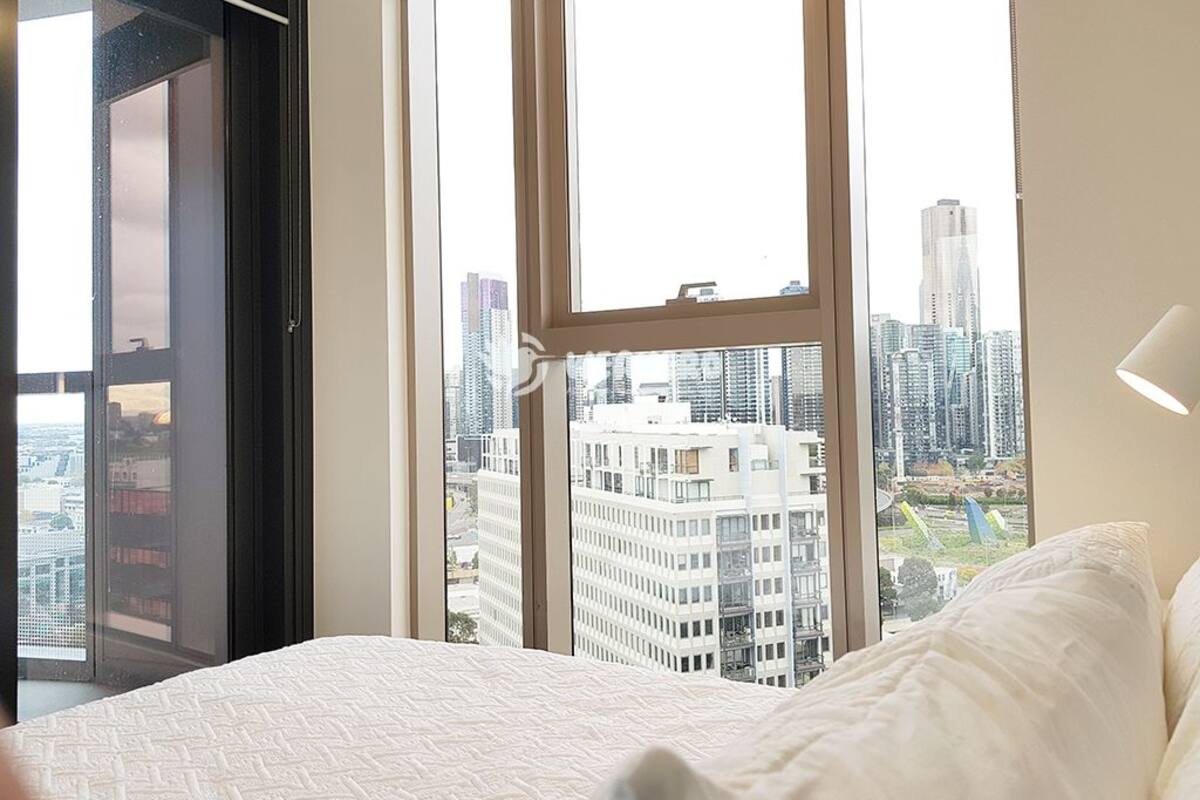 A bedroom with a large window offering a city view.