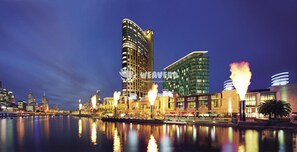 A modern hotel with a curved facade, a reflection pool, and a waterfront view. - Modern Living in Southbank Apartments (Southbank)