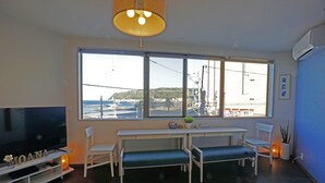 Un salon doté d’une grande fenêtre, d’un téléviseur et d’un espace détente avec des bancs.