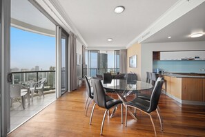 Un apartamento moderno con balcón, zona de comedor con mesa de vidrio y cocina con armarios de madera.