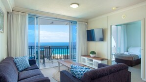 Una habitación de hotel moderna con balcón, un conjunto de sofás, una mesita y una cama.