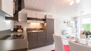 A modern kitchen with a built-in microwave, a sink, and a glass dining table.