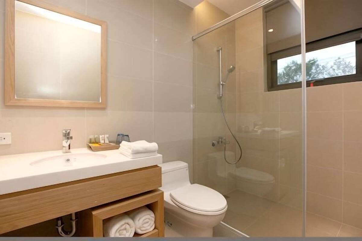 A modern bathroom with a glass shower enclosure, a wooden vanity, and a large mirror.