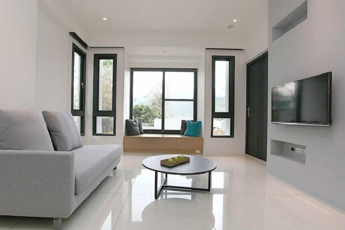 A modern living room with a grey sofa, a round coffee table, and a large TV on the wall.
