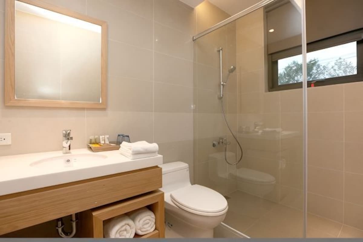Un baño moderno con cabina de ducha de vidrio, tocador de madera y un espejo grande.