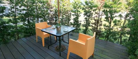 Un patio al aire libre con una mesa y dos sillas, rodeado de follaje.