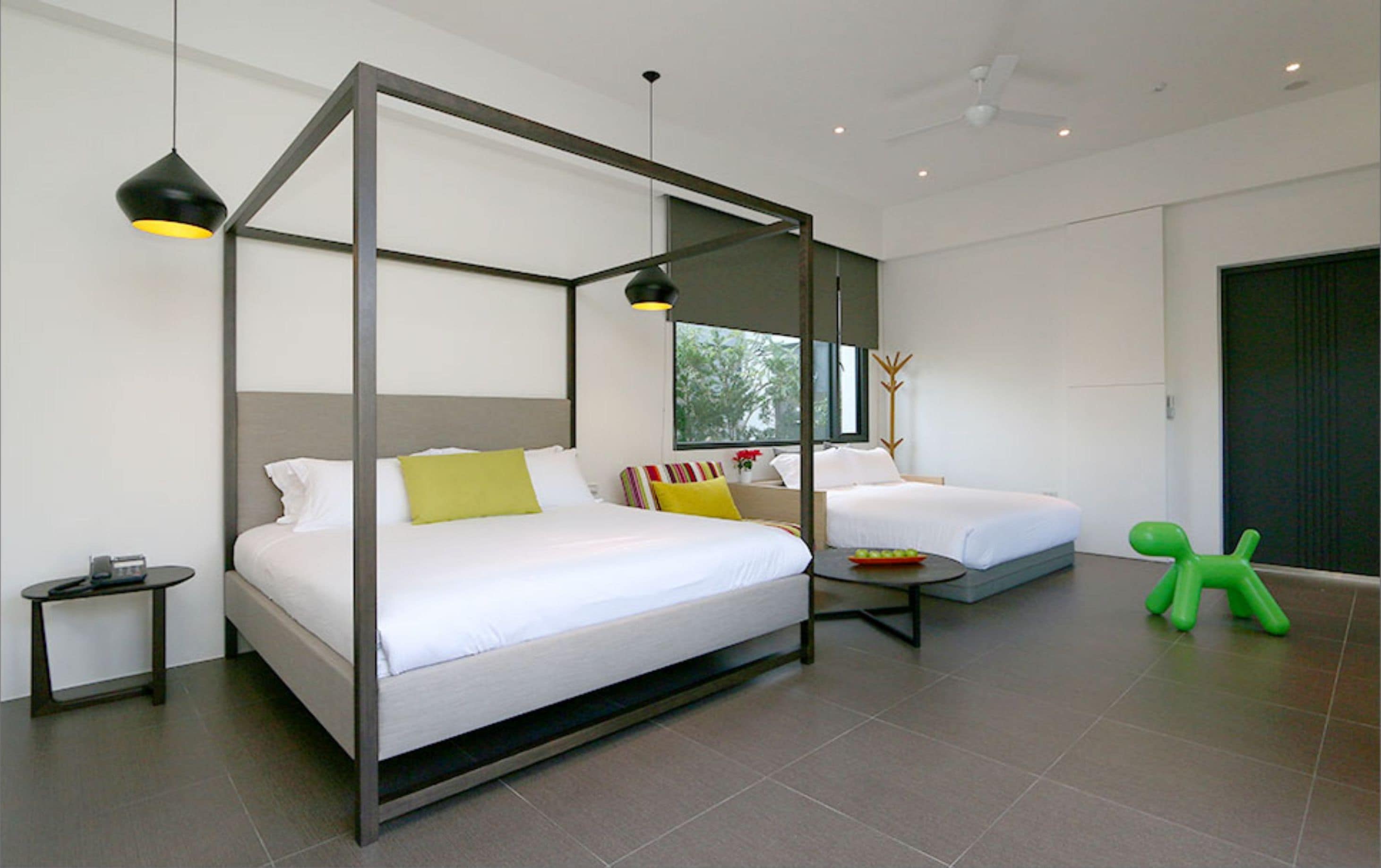 A modern bedroom with a four-poster bed, a smaller bed, and a green toy figure.