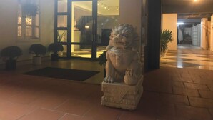 A stone lion statue in front of a building with a checkered floor and a glass door entrance. - Hotel Pure (Hai Phong)