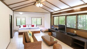 A bedroom with a bed, bedside tables, a TV, and large windows. - Fukugi Terrace (Motobu)