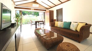 A living room with a sofa, coffee table, and TV. - Fukugi Terrace (Motobu)