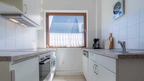 Una cucina compatta con forno a incasso, lavastoviglie e una finestra vista casa.