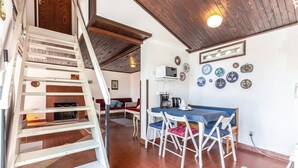 Ein gemütliches Zimmer mit einer Holztreppe, einem Essbereich mit Tisch und Stühlen sowie einer Küchenzeile mit Mikrowelle und Kaffeemaschine.