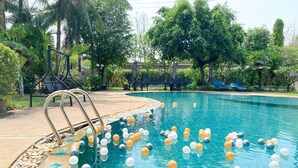 A swimming pool with a metal ladder, surrounded by palm trees and lounge chairs.