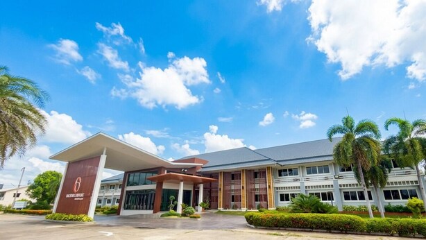 A modern building with a large entrance, palm trees, and a clear blue sky.