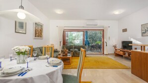 Un coin repas avec une table ronde pour quatre personnes, un canapé et un meuble pour la télévision.