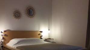 Makuuhuoneessa on puinen sänky, yöpöytä, jossa on lamppu, sekä kaksi seinälle kiinnitettyä koristepeiliä.