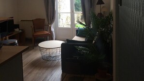 Olohuone, jossa on suuri ikkuna, pyöreä pöytä, sohva ja televisio.