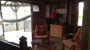 A cozy room with a wooden bench, a glass table, and a plaid-patterned chair. - Authentic and comfortable Martinique Villa with pool, 400m from the beach  (Sainte-Anne)