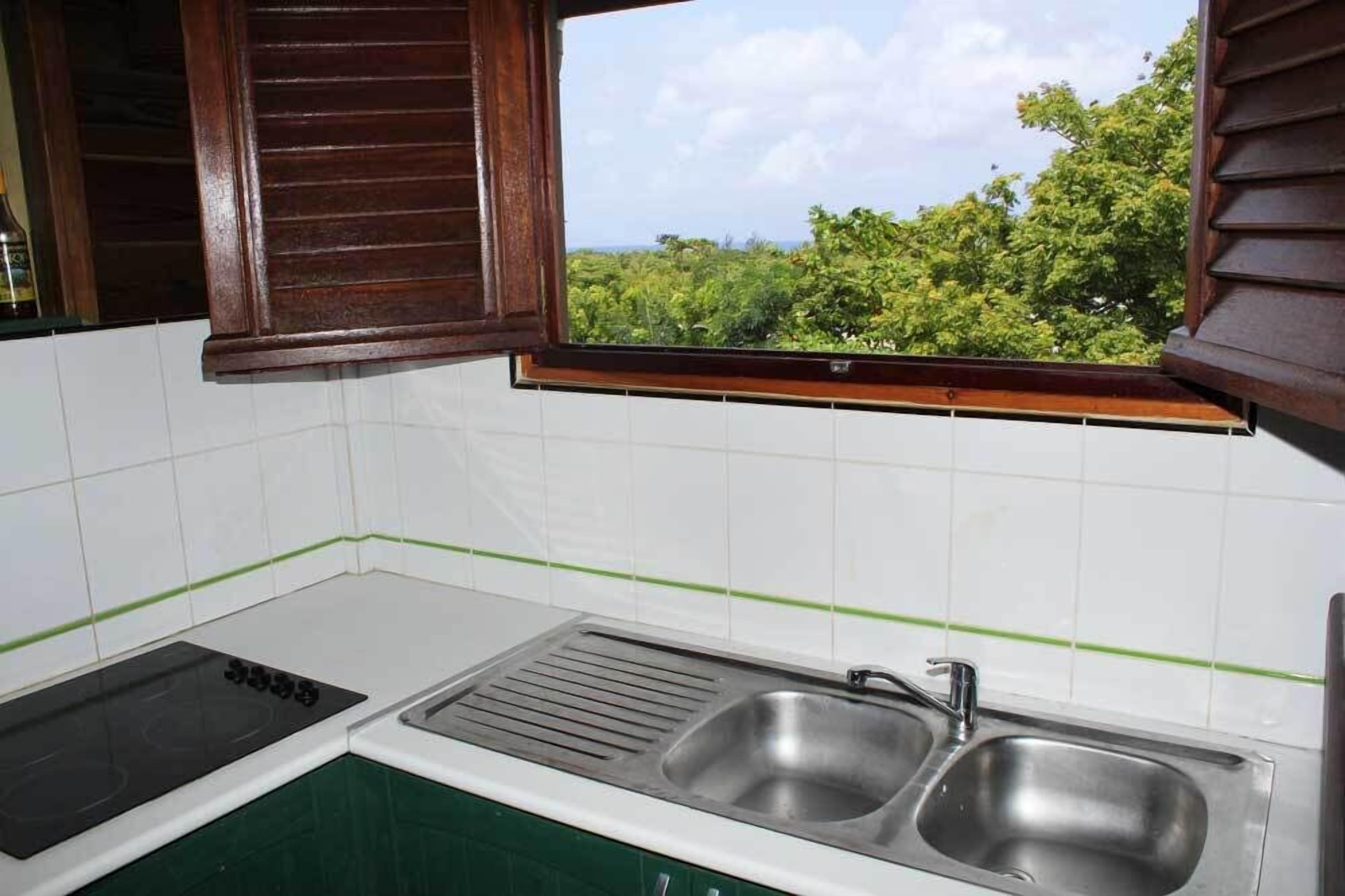 A kitchen with a window, a sink, and a stovetop.