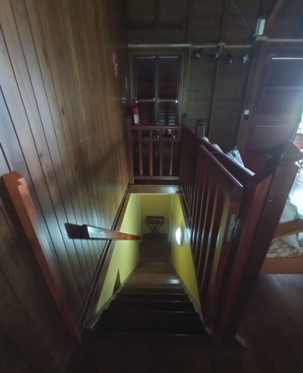 Un escalier étroit en bois, muni d’une main courante, qui mène à une porte située en haut.