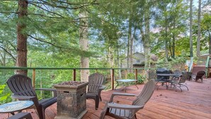 A wooden deck with outdoor furniture, a stone fire pit, and a view of a forested area. - Lone Star Retreat # 1-10 min to Waynesville & BR Pkwy-25 min to Biltmore Estate (Lake Junaluska)