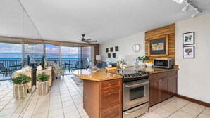 Una cucina moderna con una grande isola, elettrodomestici in acciaio inossidabile e vista all'esterno.