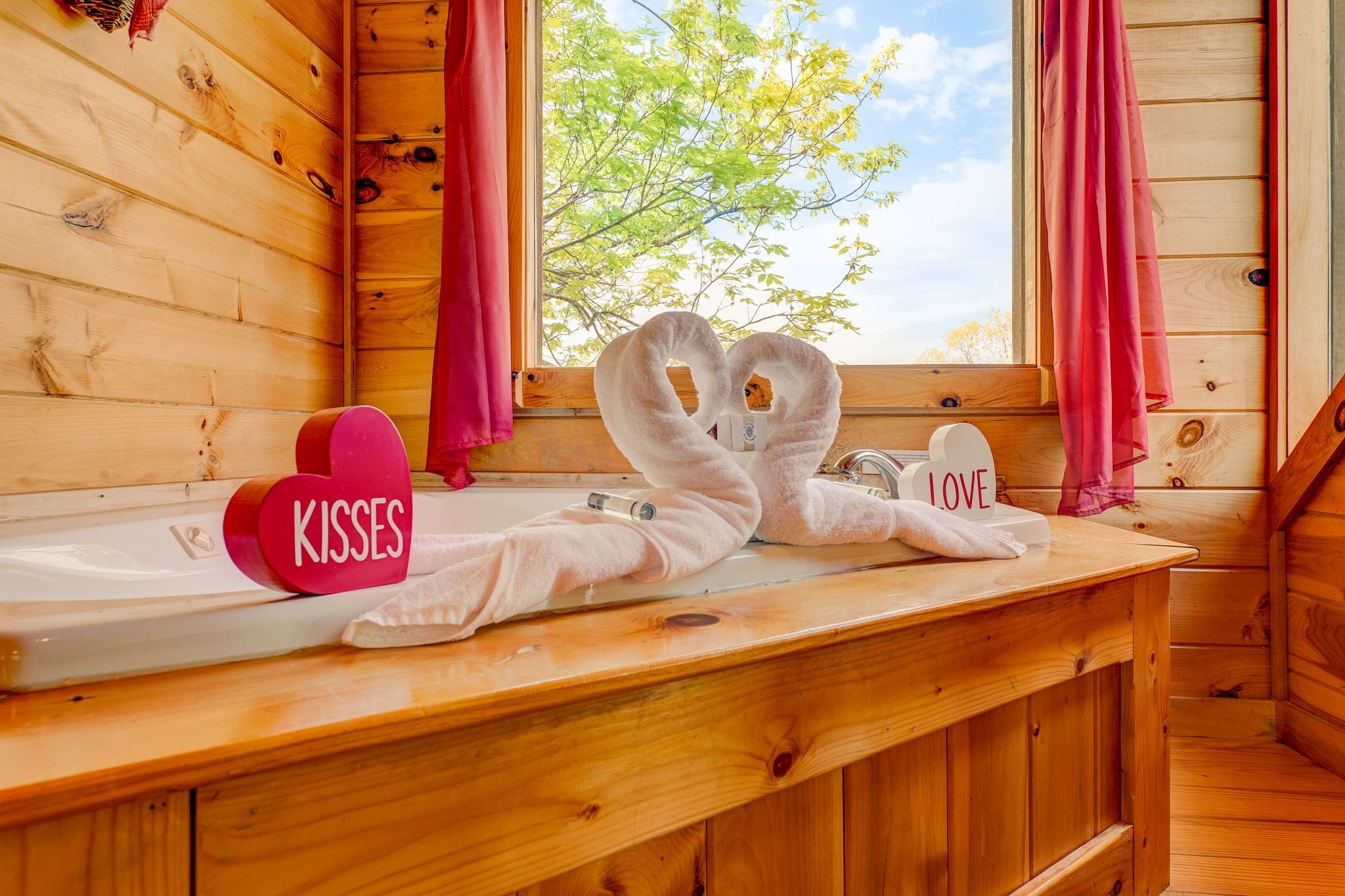 Baño de cabaña de madera con vista por la ventana, un perchero y una toalla con la palabra 'LOVE'.