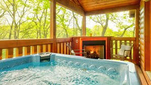 A hot tub on a wooden deck with a view of trees.