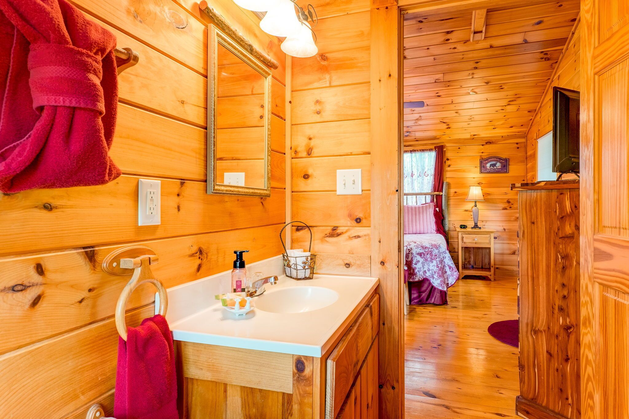 L’intérieur d’un chalet en bois comprend une salle de bain équipée d’un lavabo, d’un miroir et d’un porte-serviettes.