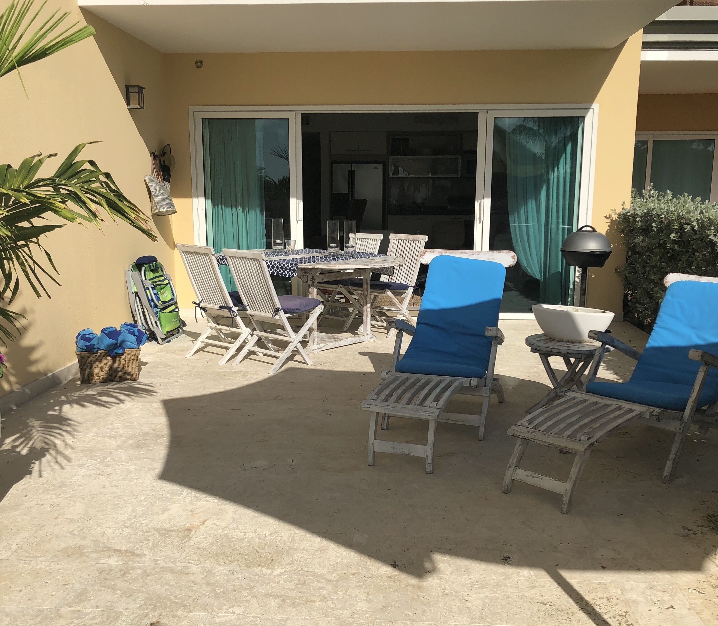 An outdoor patio with a table and chairs, a grill, and a wheelchair.