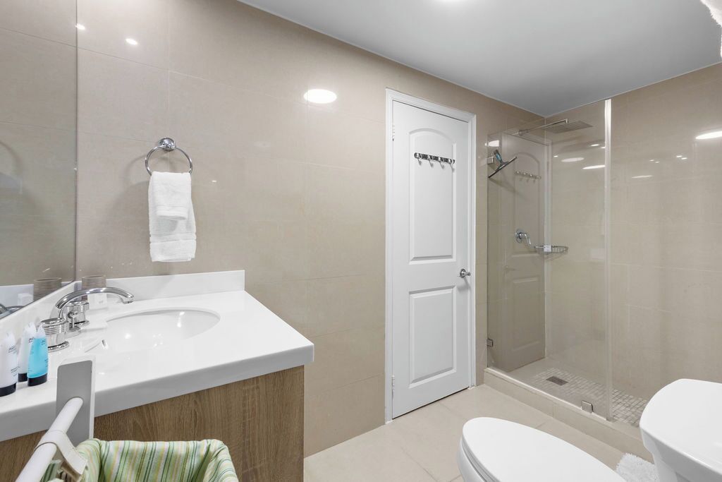 Un baño moderno con lavamanos, inodoro y zona de ducha.