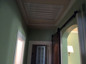 Stroll down this charming hallway with a sloped ceiling, leading to a door with a frosted glass panel.
