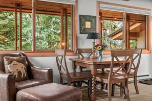 A dining area with a wooden table, chairs, and a lamp. - RMR: La Choumine 8 Condo in Teton Village / Steps from the Mountain! (Teton Village)