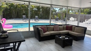 A covered patio with a pool, wicker furniture, and outdoor chairs. -  Paradise Cove -- A perfect Beach Getaway (Bradenton)