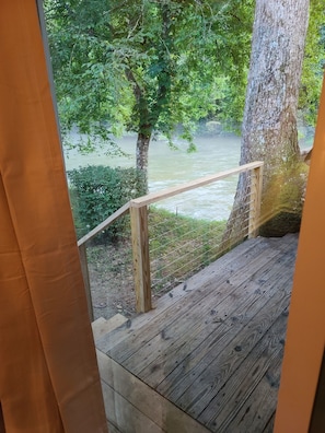 Enjoy serene views of the river from this deck, surrounded by lush greenery and trees.