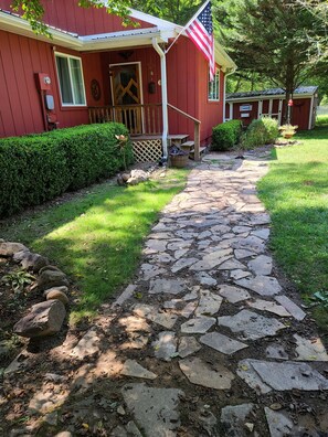 Stroll up the stone pathway to the front door of this charming home, featuring a cozy porch and a beautiful garden.